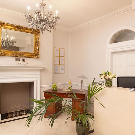 Montcalm Brewery Townhouse Hotell London Exteriör bild The photo shows a stylish reception area. There is a decorative chandelier hanging from the ceiling, providing elegant lighting. A large, ornate mirror is mounted on the wall beside the fireplace, which features a simple, classic design. In front of 