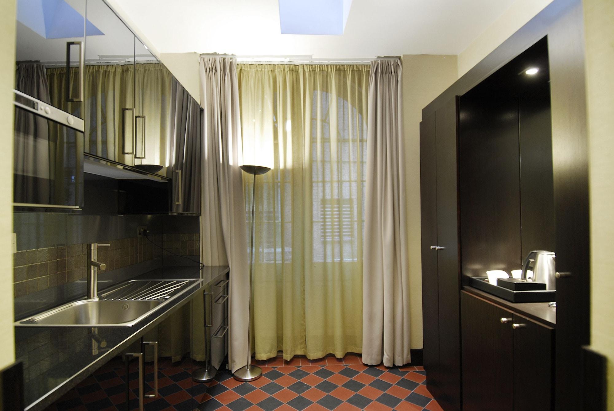 Montcalm Brewery Townhouse Hotell London Exteriör bild The photo shows a modern kitchen space. On the left side, there is a sleek countertop and kitchen cabinets in a dark finish. The backsplash appears shiny, reflecting the surroundings. To the right, there is a tall black cabinet. A window is covered w
