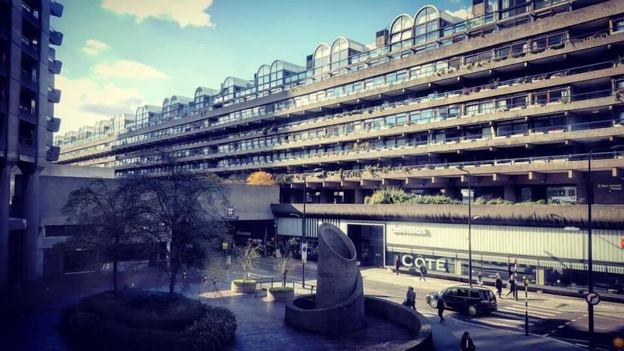 Montcalm Brewery Townhouse Hotell London Exteriör bild The photo shows a modern architectural structure with multiple levels, featuring a series of large, rectangular balconies. Below this building, there is a plaza or courtyard area with a sculptural piece, which appears to be made of stone. Surrounding