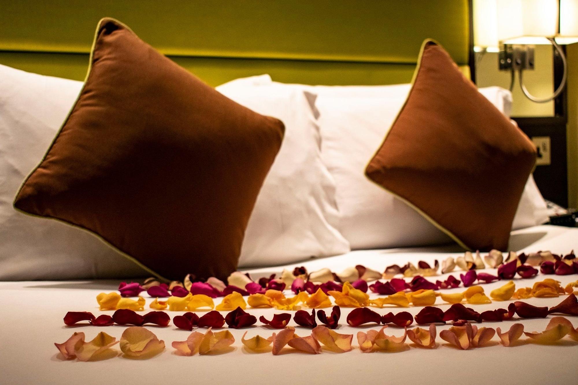 Montcalm Brewery Townhouse Hotell London Exteriör bild The photo shows a neatly arranged bed with two white pillows and brown decorative cushions. Scattered across the bed is a decorative display of flower petals in various colors, including pink, yellow, and orange, creating a romantic or tranquil ambia