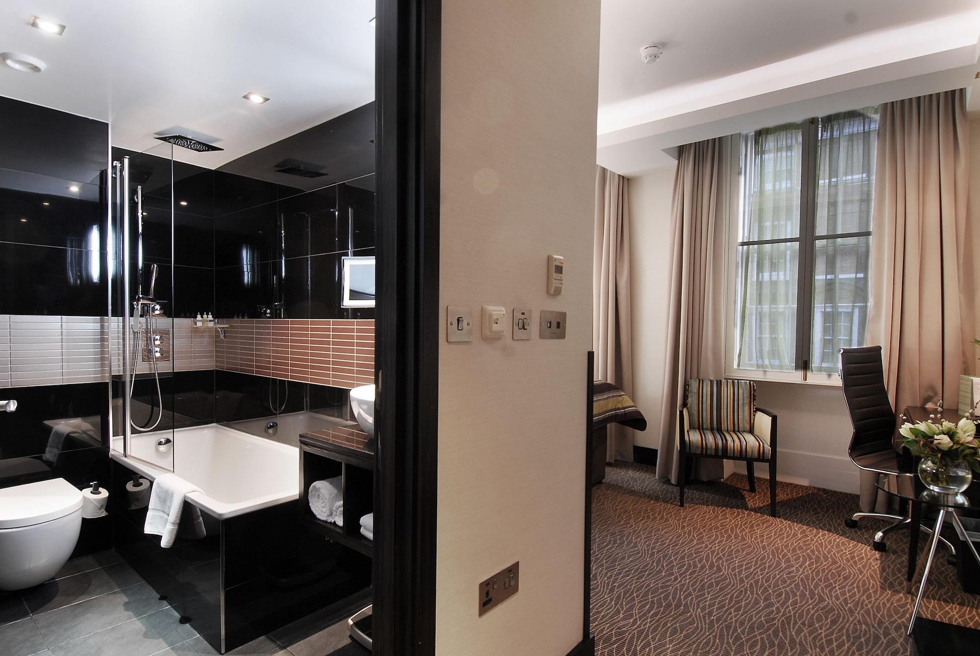 Montcalm Brewery Townhouse Hotell London Exteriör bild The photo shows a modern hotel room that features an elegant bathroom on one side and a living area on the other. 

1. **Bathroom**: The bathroom is stylishly designed with a combination of black and white tiles. It includes a bathtub, a shower area 