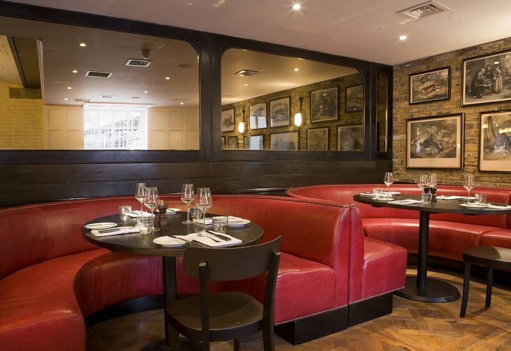 Montcalm Brewery Townhouse Hotell London Exteriör bild The image shows the interior of a restaurant featuring a warm and inviting atmosphere. There are several round tables surrounded by black chairs, with red, upholstered booths lining the walls. The decor includes framed artwork hanging on the walls, a