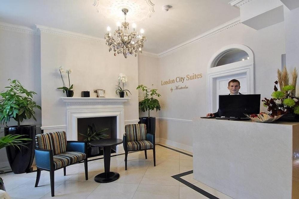 Montcalm Brewery Townhouse Hotell London Exteriör bild The photo shows the interior of a reception area in a hotel called "London City Suites." The space features a light-colored wall with the hotel's name displayed. There is a stylish chandelier hanging from the ceiling, providing warm lighting. 

In th