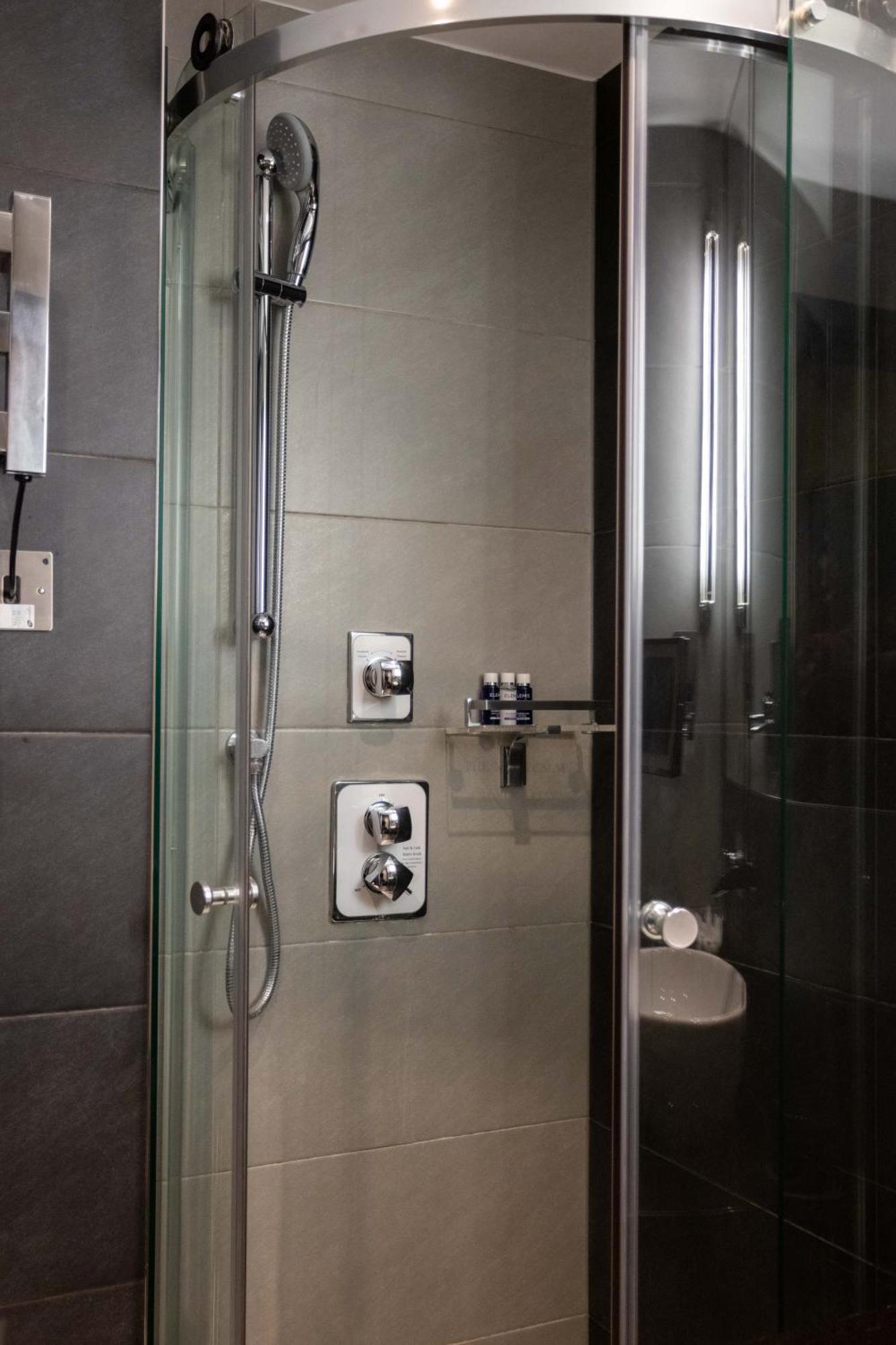 Montcalm Brewery Townhouse Hotell London Exteriör bild The photo shows a modern shower area. It features glass panels and tiled walls in a neutral color palette, creating a sleek and contemporary look. There are two main control panels for adjusting the water temperature and pressure, with various knobs 