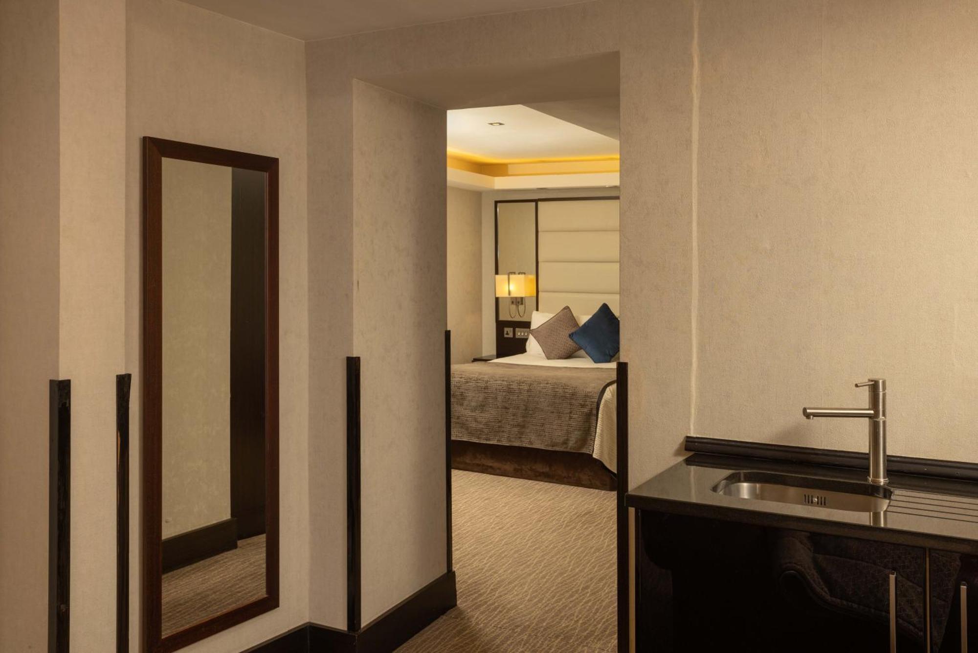 Montcalm Brewery Townhouse Hotell London Exteriör bild The photo shows an interior space that appears to be part of a hotel room or suite. There is a doorway leading into a bedroom area, where a bed with decorative pillows is visible. In the foreground, there's a tall mirror on the left side and a small 