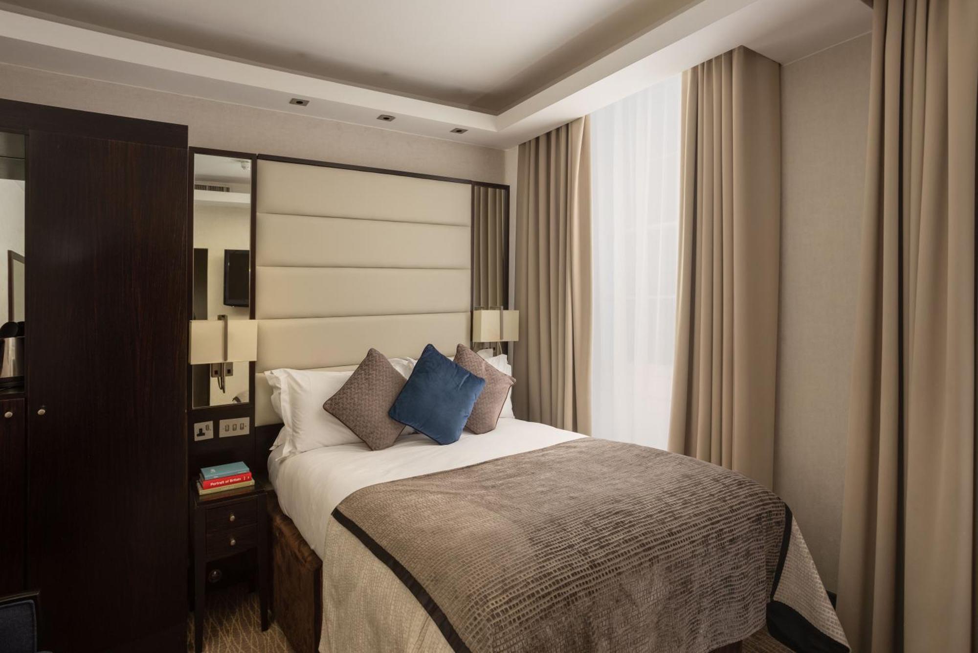 Montcalm Brewery Townhouse Hotell London Exteriör bild The photo shows a modern hotel room with a cozy design. It features a double bed with a light-colored headboard and a soft, stylish blanket. There are decorative pillows on the bed, including a blue one. On either side of the bed, there are small nig