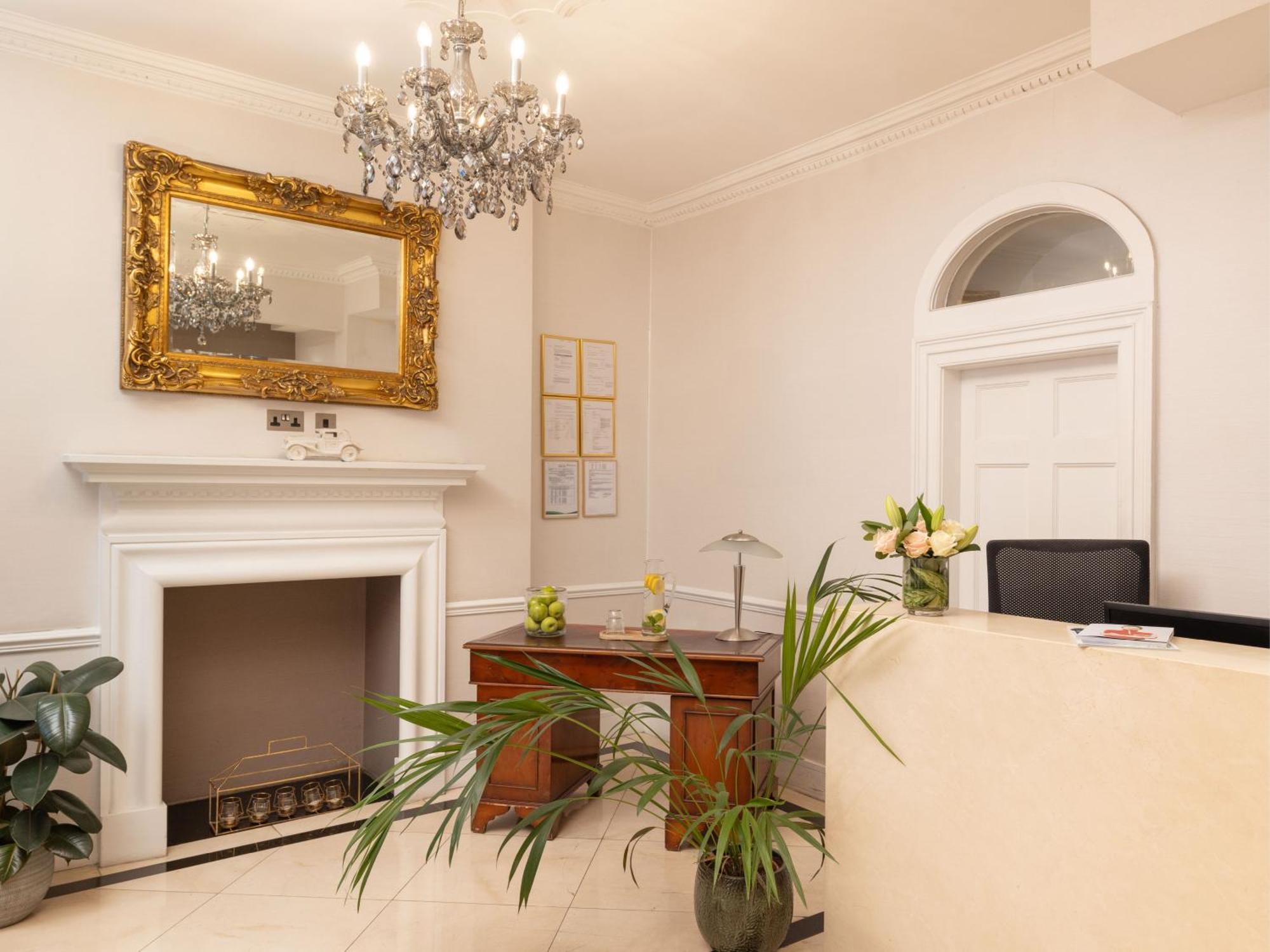 Montcalm Brewery Townhouse Hotell London Exteriör bild The photo shows a stylish reception area. There is a decorative chandelier hanging from the ceiling, providing elegant lighting. A large, ornate mirror is mounted on the wall beside the fireplace, which features a simple, classic design. In front of 