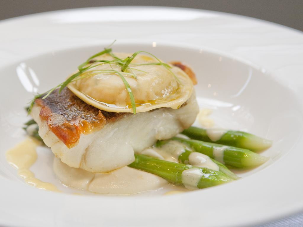 Montcalm Brewery Townhouse Hotell London Exteriör bild The image shows a beautifully presented dish featuring a piece of fish, likely a white fish, topped with a clam. It is served on a bed of green asparagus spears. The dish is garnished with thinly sliced herbs or greens, adding a touch of color. The s