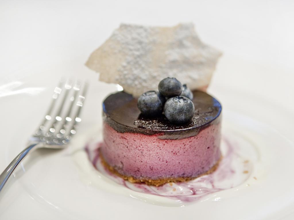 Montcalm Brewery Townhouse Hotell London Exteriör bild The photo shows a beautifully plated dessert, which appears to be a round cheesecake or mousse. It has a pinkish-purple filling, topped with a glossy dark chocolate layer. Three fresh blueberries sit on top, adding a pop of color. The dessert is acco