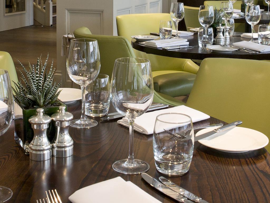 Montcalm Brewery Townhouse Hotell London Exteriör bild The photo shows a dining setup in a restaurant. There are tables with a polished wooden surface and elegant place settings. Each setting includes multiple wine glasses and water glasses, neatly arranged with folded napkins. 

In the center, there are