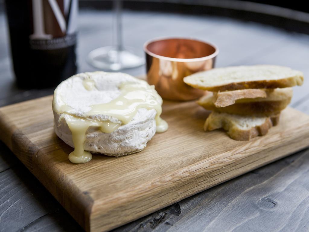 Montcalm Brewery Townhouse Hotell London Exteriör bild The photo features a wooden serving board with several items. There is a round cheese, likely Brie or a similar soft cheese, that appears to be melting and dripping slightly. Next to the cheese, there is a small copper cup that might contain a sauce 