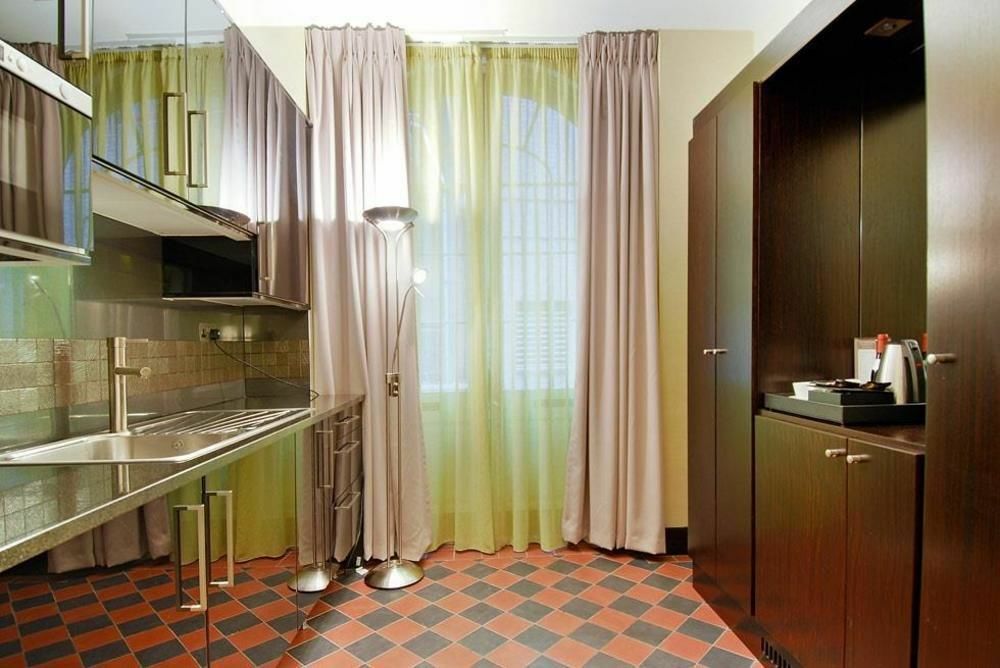 Montcalm Brewery Townhouse Hotell London Exteriör bild The photo shows a modern kitchen area. There is metallic cabinetry and a stainless steel countertop with a sink. The walls are adorned with light-colored curtains that allow natural light to filter in, with one set in a soft purple hue and another in