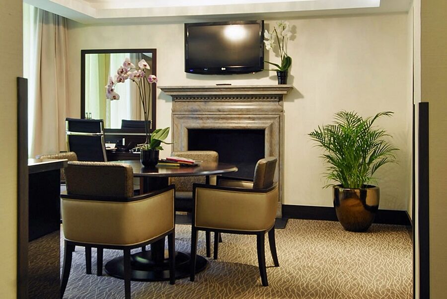 Montcalm Brewery Townhouse Hotell London Exteriör bild The photo shows a modern and stylish room with a dining or meeting area. There is a round table surrounded by four upholstered chairs. A flat-screen television is mounted on the wall above a decorative fireplace. To the side, there is a mirror reflec